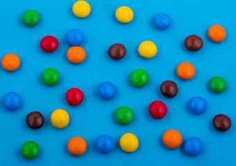 bright background made of colored chocolate candy on a blue background