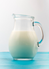 Glass jug full of fresh white milk on white background