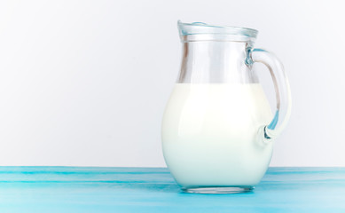 Glass jug full of fresh white milk on white background with copy space