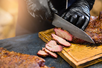 Culinary master class. Cropped shot of chef in black cooking gloves using knife to slice smoked beef brisket. - obrazy, fototapety, plakaty