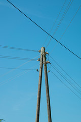 ein einfacher Holzmast mit Stromdrähten, Strommast vor blauem Himmel