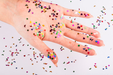 Naklejka na ściany i meble girl's hand with beautiful sequins of different shapes on white background