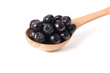 Chokeberry in wooden spoon isolated on white background. Black aronia