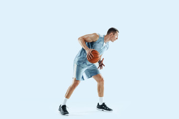 Winner. Young caucasian basketball player of team in action, motion in jump isolated on blue background. Concept of sport, movement, energy and dynamic, healthy lifestyle. Training, practicing.