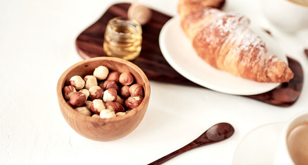 Hazelnut in brown bowl on textured wooden background, top view.