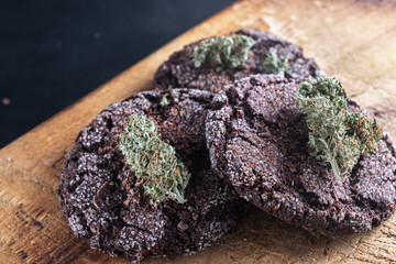 three chocolate chip cookies with marijuana lie on a wooden dish
