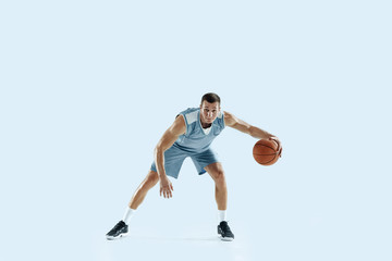 Champion. Young caucasian basketball player of team in action, motion in jump isolated on blue background. Concept of sport, movement, energy and dynamic, healthy lifestyle. Training, practicing.