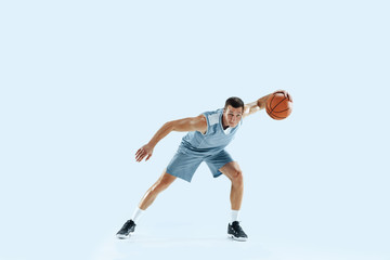 Champion. Young caucasian basketball player of team in action, motion in jump isolated on blue...
