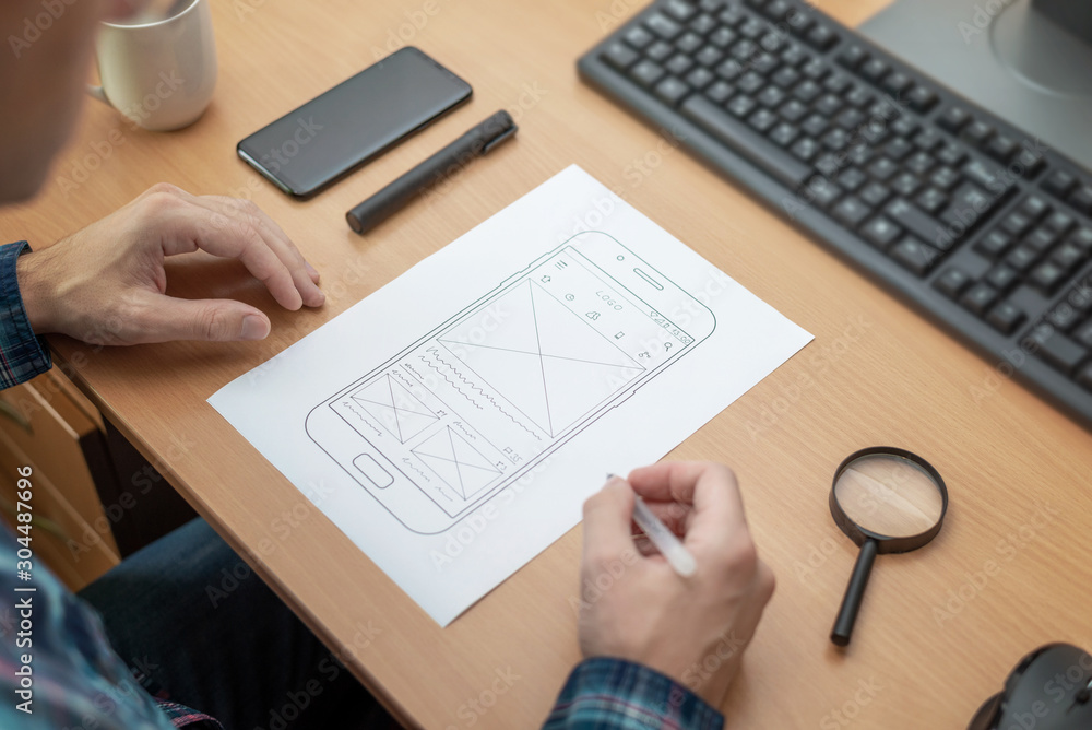 Poster The designer sketches, draws the layout of a mobile phone app on a wireframe..