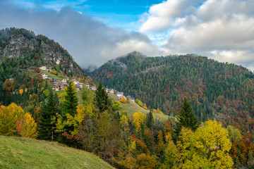 Colourful aumtumn view across the Cordevole valley with the villages of Pecol and Piaia in the background in Belluno, Italy