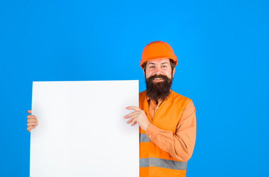 Construction worker, engineer, architect with blank board. Builder, repairman in protective helmet holds empty board with space for text. Man builder holds advertising banner, billboard, sign board.