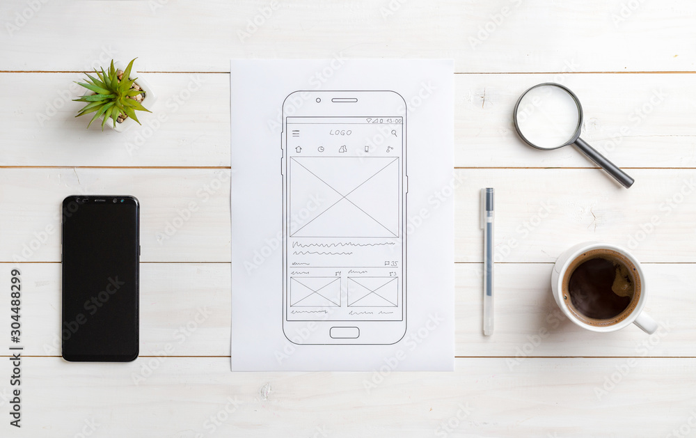 Poster Sketch of mobile app on paper. Top view scene of web designer desk. The concept of user interface design. Smart phone beside.