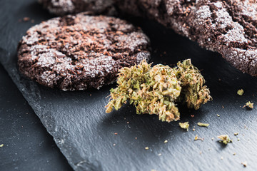 chocolate chip cookies with marijuana, sprinkled with chocolate chips and cannabis, are on a slate dish.