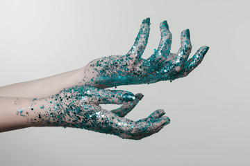 Beautiful woman hands with blue glitter in front of black, can be used as background