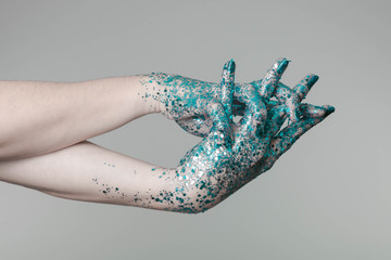 Beautiful woman hands with blue glitter in front of black, can be used as background