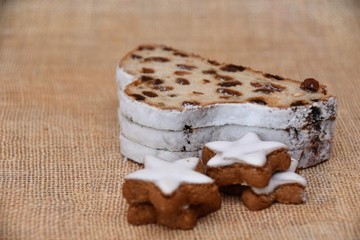 Christmas German traditional pastries, cinnamon stars with and stollen with raisins on a background of natural canvas