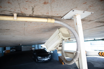 Security CCTV camera under ceiling operating in car park. Security and surveillance system concept.