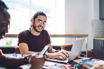 Young student with laptop at desk with group mate