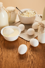 tasty organic dairy products and eggs on rustic wooden table isolated on beige