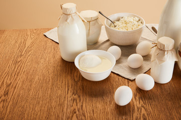 various fresh organic dairy products and eggs  on rustic wooden table isolated on beige