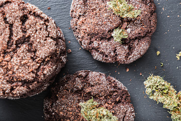 chocolate chip cookies with marijuana, sprinkled with chocolate chips and cannabis, are on a slate dish.