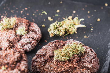 chocolate chip cookies with marijuana, sprinkled with chocolate chips and cannabis, are on a slate dish.