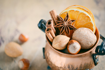 Christmas spices, nuts and dried oranges on a wooden background.