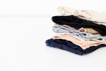 Stack of different colour women's panties lying on a white table. Women underwear background. Copy space