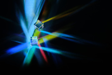 cubic glass prism refracting light rays on a dark background