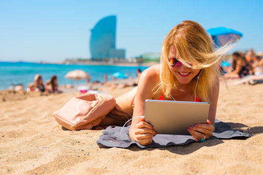 Woman watching movie on tablet computer while sunbathing on the beach