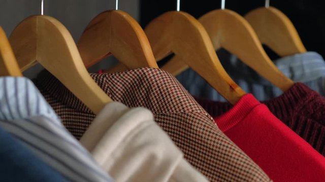 Hangers with different clothes in wardrobe closet. Shopping concept. Slider shot