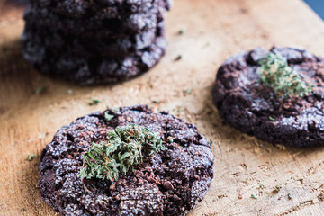 chocolate chip cookies with marijuana, sprinkled with chocolate chips and cannabis, are on a slate dish.