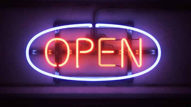 Flickering red and blue neon open sign glowing on a dark wall