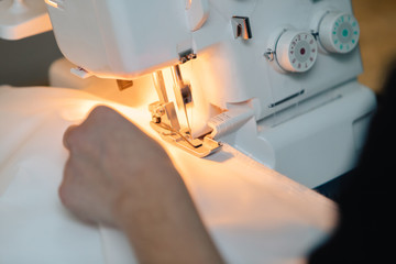 Hand holding fabric and sewing machine.