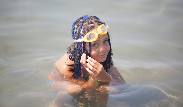 Little girl with dreadlocks plays in the sea with a sea cucumber