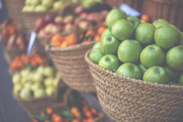 Market stall with variety of organic vegetable. Fresh organic produce on sale at the local farmers market. Ripe organic apples in a basket.