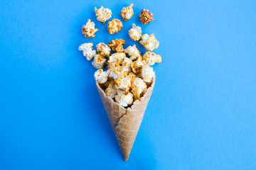 Ice cream cone with caramel popcorn in the center of  the blue  background. Top view. Copy space.