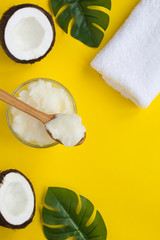 Spa composition. Coconut oil , white towel and coconut halves on  the yellow  background. Natural product. Top view. Copy space. Location vertical.