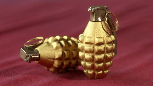MK2 hand grenades. Two golden pineapple grenades on the red velvet cloth.
