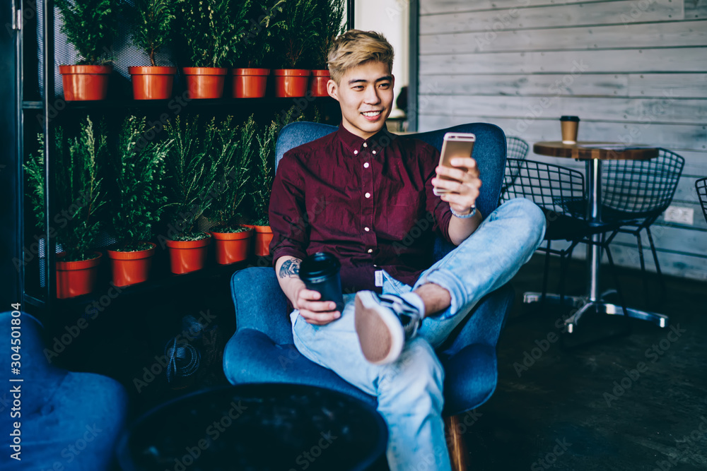 Aufkleber positive chinese hipster blogger holding coffee to go in hand while reading funny notification on mo