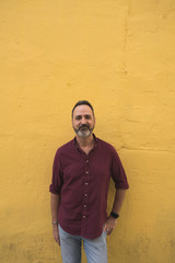 Man with gray beard over yellow wall