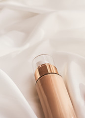 Tonal bb cream bottle make-up fluid foundation base for nude skin color on silk background,...