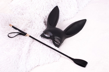 leather rabbit mask and  whip on the bed