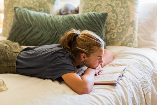 Girl lying on her hands and reading book
