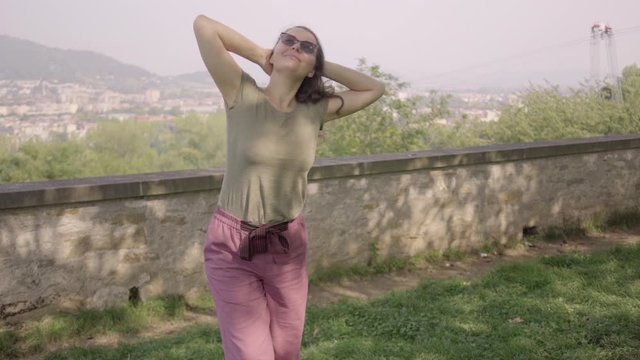 Beautiful woman walking in small Italian city. Girl walking and looking around. Slow motion video Happy model in good mood at vacation