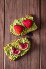 avocado toasts with fruits on rustic wood