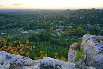 Fototapeta na wymiar Sunset view of the Alpilles valley with green olive tree groves below the historic fortified village Les-Baux-de-Provence, in Bouches du Rhone, Provence, France.