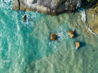 Aerial view of turquoise waves beating on stones. Thailand