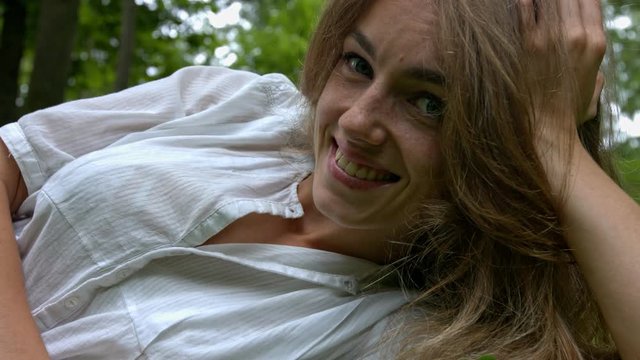 looking woman in white blouse smiling while lying down, still close up shot