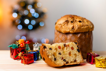Delicious Panettone slice with candied fruits with blinking blurred christmas lights. Dry fruits. Ornament and tree gifts.